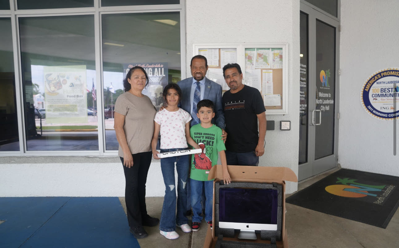 A family receives an iMac from the Mayor at City Hall