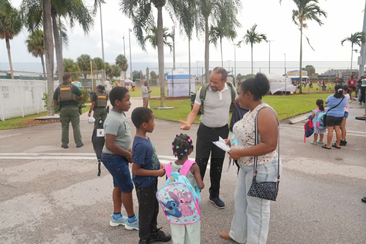 Mayor Borgelin greets a family with children wearing backpacks