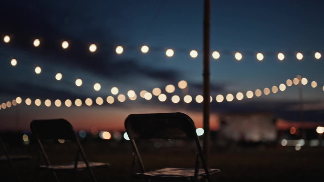 String lights glowing over a community event at dusk